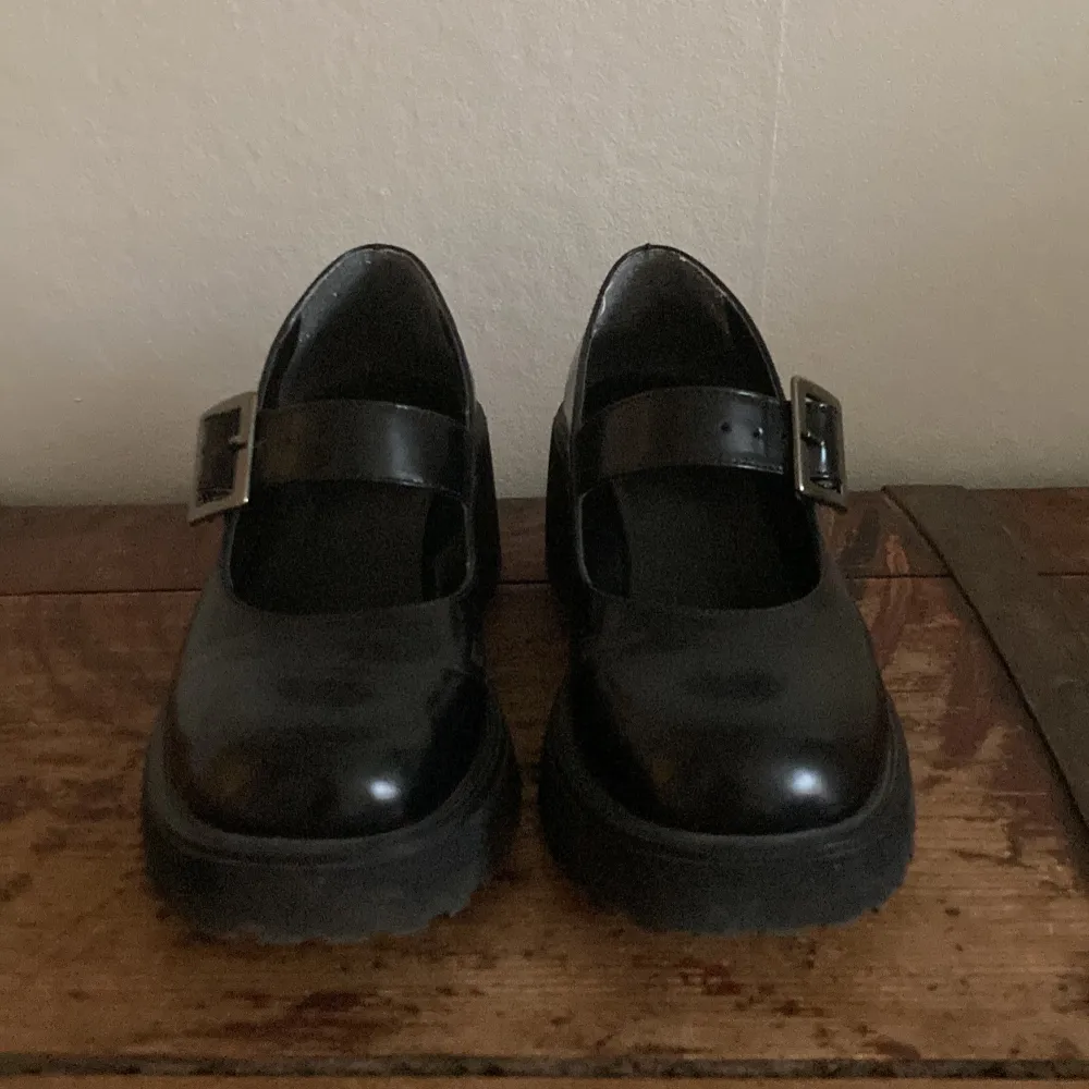 Säljer ett par chunky svarta Mary Jane skor  med bred klack och silverfärgat spänne. Skorna har rund tå och platt sula, perfekta för dig som gillar en edgy och stilren look.. Kengät.