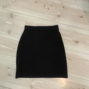Svart pennkjol - En klassisk svart pennkjol med hög midja och rak passform. Kjolen är enkel och stilren, perfekt att matcha med olika toppar. 