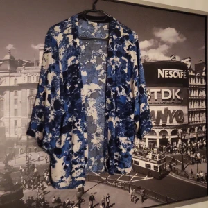 Blåvit mönstrad kimono-jacka - Säljer en luftig och oversized kimono-jacka med blått och vitt abstrakt mönster. Jackan har trekvartsärmar och öppen front, perfekt att slänga över en enkel outfit för en cool look.