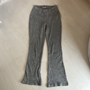 Grå ribbade byxor från 157 - Säljer ett par grå ribbade byxor från 157 i storlek XS. Byxorna har en bekväm passform med utsvängda ben och elastisk midja. Perfekta för en avslappnad och trendig stil.
