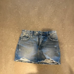 Blå jeanskjol med slitningar - Säljer en blå jeanskjol från Pull & Bear med slitna detaljer. 