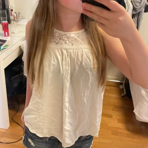 Vit spets topp - Säljer en söt vit blus från KappAhl med spetsdetaljer upptill. Blusen är ärmlös och har en lös passform, perfekt för varma dagar. Materialet känns lätt och luftigt. Perfekt för sommaren! Hör av er vid frågor! Ni får gärna trycka på köp nu!❤️Storlek 152 men sitter som Xs/s