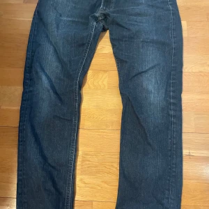 Mörkblå jeans Luke W34 L34 - Säljer ett par mörkblå jeans från Luke i klassisk straight modell. Jeansen har fem fickor, normal passform och subtila slitningar framtill. Perfekta till vardags för en stilren look.