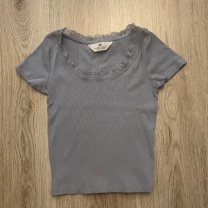 Ribbad topp - Säljer en ljusblå ribbad topp från H&M med korta ärmar och fin spetskant runt den runda halsringningen. Säljer då jag inte har haft mycket användning av den tyvärr. Skriv om du har frågor o läs gärna min bio innan du köper🫶🏻🫶🏻
