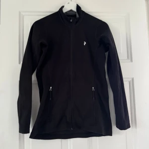 Svart fleecejacka från Peak Performance - Svart fleecejacka från Peak Performance med hel dragkedja framtill och två fickor med dragkedja. Storlek S, Aldrig använd.