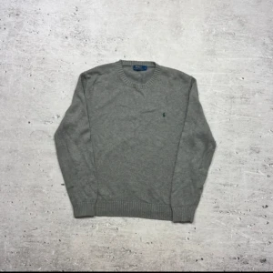 Grå stickad tröja från Polo Ralph Lauren - Hej! Säljer en snygg klassisk grå stickad tröja från Ralph Lauren. Tröjan har en grön häst och är i färgen grå. Skicket på tröjan är enligt mig rätt bra. Passformen på tröjan ser ni på bilderna, lite kort är den på mig!  Perfekt för en stilren och enkel look. Vid fler frågor är det bara att höra av er!