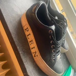 Svarta Philipp Plein skor  - Säljer ett par svarta sneakers från Philipp Plein.  logga på sidan. Det står Plein på sidorna av båda skrorna och har platta framtill. Dom är äkta men har ej kvitto därav priset. Kan diskuteras 