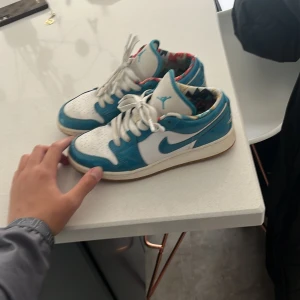 Nike Air Jordans i blått och vitt - Säljer ett par Nike Air Jordans i blått och vitt med vit snörning och färgglad innerfoder. Skorna har klassisk rund tå och platt sula, perfekt för dig som gillar streetwear och sneakers med unik design.