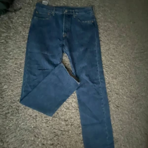 Levi's 501 blå jeans - Klassiska blå Levi's 501 jeans med raka ben och femficksmodell. Jeansen har normal passform och är tillverkade i slitstarkt denimtyg. Perfekta för en tidlös och avslappnad stil. Använd endast 1 gång. Storlek W33/L34. Nypris 899