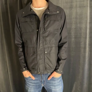 Mörkblå fieldjacket från Five Seasons - Säljer en mörkblå fieldjacket från Five Seasons med flera praktiska fickor och dragkedja framtill. Jackan har hög krage och diskret logotyp på ärmen. Perfekt för kalla dagar och enkel att matcha med olika outfits. Stor i storleken så passar mer en L. Skick 8/10✅ Pris kan diskuteras vid snabb affär💸