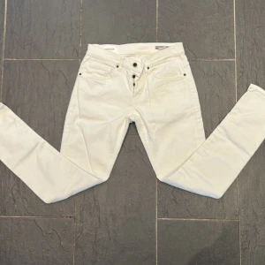 Vita slimfit jeans från Dondup, - Snygga vita jeans från Dondup, modell George. Byxorna är slimfit, knäppning med knappar och klassisk femficksdesign. Perfekta för dig som vill ha en stilren och fräsch look.