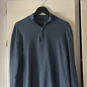 Blå half zip tröja Oscar Jacobson - Snygg blå långärmad tröja från Oscar Jacobson med half zip-dragkedja i halsen. Tröjan har en stilren design och är tillverkad i ett mjukt bomullsmaterial. Perfekt för dig som gillar klassisk men avslappnad stil.
