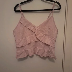 Ljusrosa volang topp med smala axelband - Supersöt ljusrosa linnetopp från shein volangdetaljer framtill och baktill. Toppen har smala axelband, croppad passform och dragkedja i sidan. Perfekt för varma dagar och ger en romantisk vibe till din outfit.