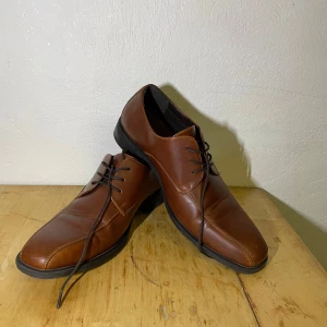 Bruna skinnloafers med snörning - Snygga bruna loafers i skinn med klassisk snörning och rund tå. Skorna har svarta detaljer på insidan och en platt sula. Perfekta för en dressad look och passar till många olika outfits. Skorna har jag använt endast en gång. 