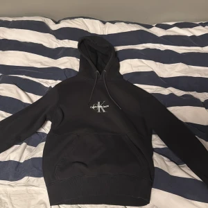 Svart hoodie från Calvin Klein  - Säljer en svart hoodie från Calvin Klein  med logga på bröstet. Tröjan har luva . Perfekt för en avslappnad och stilren look. Kan gå ner i pris vid snabba affär, hör av dig om du har frågor 