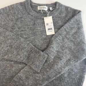 Grå stickad tröja från Carin Wester( Lindex)  - Mysig grå stickad tröja från Carin Wester i storlek XS. Tröjan har rund halsringning och långa ärmar med ribbade muddar. Perfekt för lager-på-lager och enkel att matcha med olika outfits.