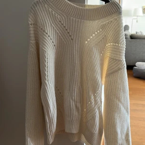 Vit stickad tröja från H&M - Säljer en vit stickad tröja från H&M med snyggt mönsterstickat material och rund halsringning. Tröjan har lång ärm och är perfekt för lager-på-lager-stil under kyligare dagar.