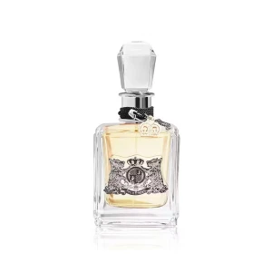 Juicy Couture Eau de Parfum 100ml - Juicy Couture Eau de Parfum i en lyxig, fyrkantig glasflaska med silverdetaljer och en stor, slipad kristallkork. Flaskan har en dekorativ etikett med lejon och krona samt ett svart band med en liten kronberlock. Innehållet är gyllene och flaskan rymmer 100 ml.
