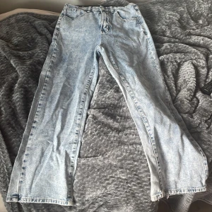 Ljusblå rbaggy jeans i vintage-stil - Säljer ett par ljusblå jeans som e baggy och klassisk femficksdesign. Materialet är klassisk denim i bomull. Har använt max 3 gånger är lite sönder trampade på högra benet som man kan se i bild.