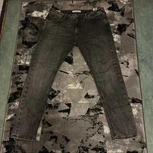 Svarta tapered jeans från Pepe Jeans - Snygga svarta jeans från Pepe Jeans med tvättad look och klassisk femficksdesign. Modellen är Tapered Stanley med smalare ben och normal passform. Jeansen är gjorda i bomull och har dragkedjegylf samt bälteshällor. Perfekta för en stilren vardagslook.