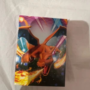 Pokémon låda med kort i - En cool temalåda med Charizard från Pokémon Sword & Shield Vivid Voltage. Perfekt för dig som vill spela Pokémonkort eller samla på unika kortlekar. Lådan innehåller en färdigbyggd lek med Charizard som huvudkort. Passar både nya och erfarna spelare.