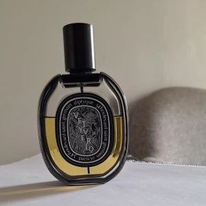 Diptyque Vetyverio  - Diptyque Vetyverio Eau de parfums är en exklusiv parfym med citrus, träiga och aromatiska noter. Flaskan är oval i genomskinligt glas med svart lock och detaljerad etikett. Doften har inslag av ros, patchouli och gröna toner för en unik och elegant känsla. Ca 45ml kvar 