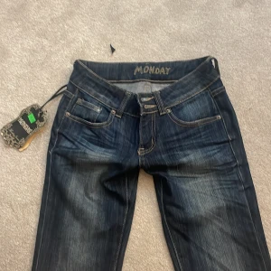 Mörkblå jeans från Monday - Säljer ett par mörkblå jeans från Monday med snygga slitningar, låg midja och raka ben.  Märkespatch i läder baktill i midjan. Dom är tyvärr för små för mig. Pris går att diskutera 