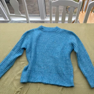 Blå stickad tröja - Säljer en snygg blå stickad tröja med rund hals och långa ärmar. Perfekt för kyligare dagar och ger en mysig känsla. Tröjan har en ribbad struktur som ger extra stilpoäng. Passar bra till jeans eller kjol för en avslappnad look.💕💕🌸🌸🤩🤩