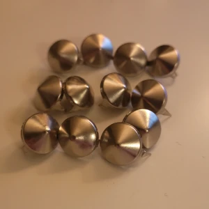 Runda silverfärgade nitar - Säljer 12 st runda silverfärgade nitar. Perfekta för att dekorera kläder eller accessoarer och är enkla att fästa med dom två spetsiga delarna på baksidan. Dom är typ 1 cm 