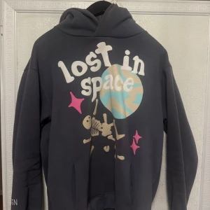 Mörkgrå hoodie med tryck - Säljer en cool broken planet mörkgrå hoodie med texten 'lost in space' och ett skelettmotiv på framsidan. Det finns även texten 'BROKEN' på ärmen. Perfekt för dig som gillar unika tryck och bekväma kläder. Priset går att diskutera 