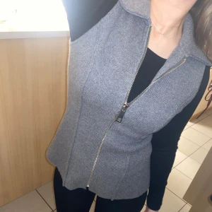 Grå stickad väst från Zara - stickad väst från Zara med dragkedja framtill. Perfekt om man gillar att layer och den passar till många olika outfits. lapparna sitter kvar och den är endast provad
