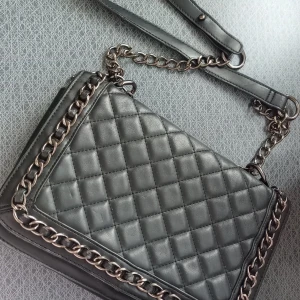 Svart axelväska - Snygg svart axelväska i quiltat mönster med kedjedetaljer. Väskan har en justerbar axelrem 🖤