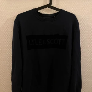 Svart tröja från Lyle & Scott - Säljer en stilren svart tröja från Lyle & Scott med deras logga diskret på bröstet. Tröjan har långa ärmar och en rund halsringning. Perfekt för en avslappnad look. Passar L/M✅ pris:130kr✅