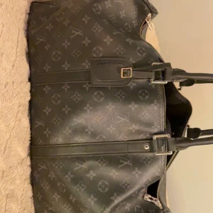 louis vuitton keepall 55 monogram eclipse - Snygg svart väska med ikoniskt mönster och detaljer i skinn. Väskan har dragkedja och spännen i metall. Perfekt för den som vill ha stil och funktion i ett.