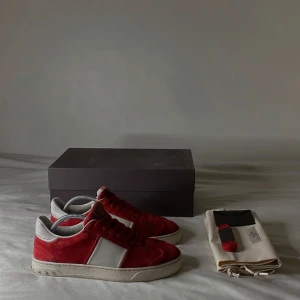 Röda Valentino Flycrews - Snygga röda Valentino Flycrews sneakers med vita detaljer och snörning. Skorna är tillverkade i mocka. Det medföljer skokartong, dustbags, extra skosnören, och även en informations bok om skorna. Två nittar saknas sammanlagt men gör ingen stor skillnad på skorna, storlek 41 men passar även en och en halv storlek större. Perfekta att använda för att skapa en stilren Outfit. Mvh 