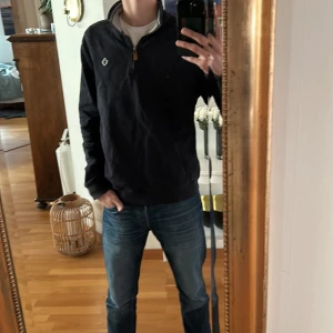 Mörk blå tröja från Morris - Snygg mörkblå tröja från Morris med dragkedja och en liten logga på bröstet. Perfekt för en stilren look. Tröjan har en hög krage. Den har i princip inga tecken på användning alls då den har använts väldigt sparsamt✅Den passar perfekt för S/M beroende på vilken look man vill ha💯