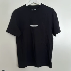 Svart t-shirt från Jack & Jones - Säljer en svart t-shirt från Jack & Jones Originals med tryck på bröstet. Perfekt för en stilren look. T-shirten är kortärmad och gjord i mjukt material. Inga defekter. 