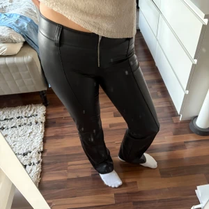 Svarta skinnbyxor - Snygga svarta lågmidjade skinnbyxor med tight passform och dragkedja fram. Stretch. Aldrig använda!