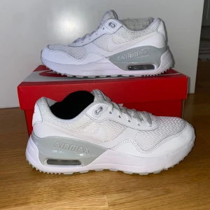 Vita Nike Air Max sneakers - Snygga vita Nike Air Max sneakers med grå detaljer. Skorna har en luftig mesh-ovandel och den ikoniska Air Max-dämpningen i sulan för extra komfort. Perfekta för en stilren look. Enbart använda inomhus, skorna är i bra skick. Innersulan från början till slut är 25.5cm