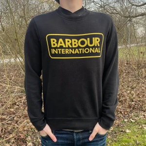 Svart tröja från Barbour International - Säljer en svart tröja från Barbour International med gul logga på bröstet. Tröjan har långa ärmar och en klassisk passform. Perfekt för en stilren look. Nypris 1099kr på care of Carl 