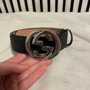 GCI bälte svart 110cm - Säljer ett helt nytt svart bälte med ett silvrigt GG spänne. Bältet är i storleken 110cm och har 7 hål på sig. Priset kan diskuteras.