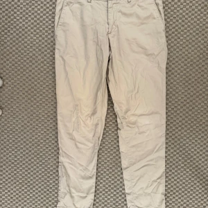 Beigea chinos från J.Lindeberg - Snygga beige chinos från J.Lindeberg med klassisk design. Byxorna har en normal passform och är tillverkade i ett bekvämt bomullsmaterial. Perfekta för en stilren look.