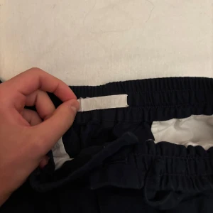 Mörkblå linnebyxor Arket - Säljer ett par mörkblå linnebyxor från Areket  med resårmidja och snörning. Byxorna har en avslappnad passform och är perfekta för en bekväm stil. De har bakfickor och är gjorda i ett mjukt material.