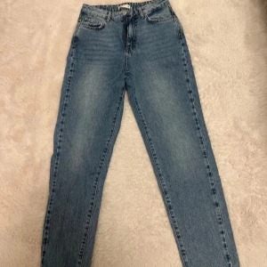 Blå jeansbyxor - Snygga blå jeansbyxor med hög midja och klassisk femficksdesign. Perfekta för en avslappnad stil med en rak passform som ger en tidlös look.