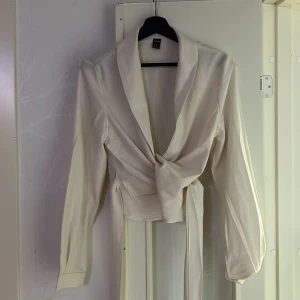 Beige omlottklänning från Shein - Säljer en elegant beige omlottklänning från Shein. Klänningen har långa ärmar och ett knytband i midjan för en smickrande passform. Perfekt för en stilren look.