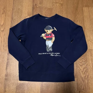 Marinblå Ralph Lauren Polo Bear Tjocktröja - Marinblå Ralph Lauren Polo BEAR tjocktröja.  ’🌟Utmärkt skick, inga tecken på användning efter en snabb tvätt.’  ’🐑100% bomull, riktigt bekvämt och stretchigt material.’  ’📬Jag skickar inom samma eller nästa dag efter köpet.’  ’📏Storlek L (14-16) för barn, men passar XS/S i vuxenstorlek till. Se mått nedan.’  ’📐42cm axelbredd, 58cm full längd, 47cm ärmlängd (alla mätt på plan mark)’  ’😊 Ställ gärna frågor.’