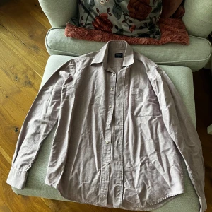 Beige skjorta från Boomerang - Säljer en stilren rosa skjorta från Boomerang i storlek M. Skjortan har långa ärmar och knappar framtill samt en bröstficka. Perfekt för en avslappnad men ändå uppklädd look.