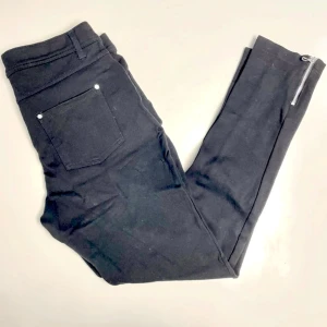 Svarta byxor från Body Flirt - Snygga svarta byxor från Body Flirt med dragkedja vid benslut och klassisk femficksdesign. Perfekta för en stilren look. Byxorna har en tight passform och är tillverkade i ett bekvämt material.