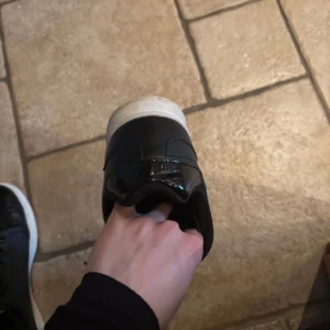 Svarta sneakers med vit sula - Snygga svarta sneakers med vit sula och snörning. Perfekta för en casual look. Skorna har en stilren design med en blank yta på tån.