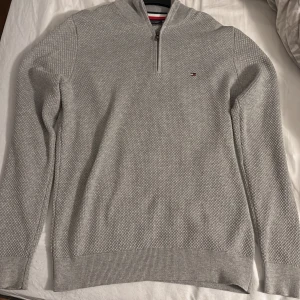 Grå tröja med dragkedja från Tommy Hilfiger - Säljer en stilren grå tröja från Tommy Hilfiger med halv dragkedja och diskret logga på bröstet. Använd ett fåtal gånger men inga defekter. Pris kan diskuteras 